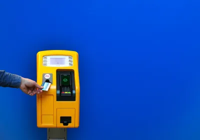 A person paying at a public transport ticket machine A person paying at a public transport ticket machine