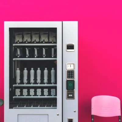 A vending machine in front of a pink wall A vending machine in front of a pink wall